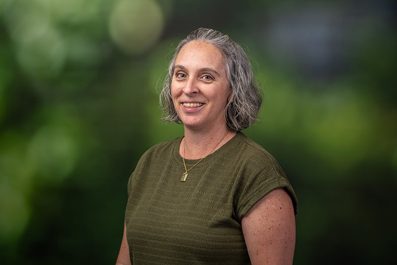 woman with shoulder-length hair wearing an olive green shirt