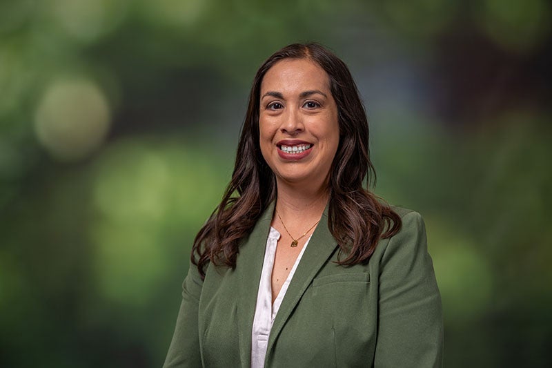 Woman with long dark hair wearing a green blazer