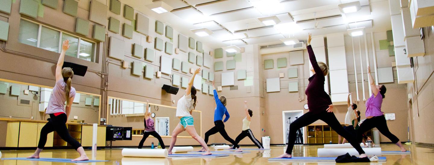 Students doing reverse warrior pose in a yoga class in the Student Recreation Center.