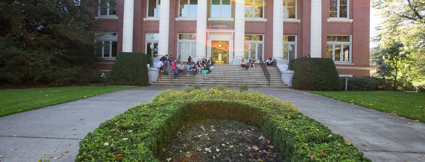 Students sit on the steps of Johnson Hall and socialize.